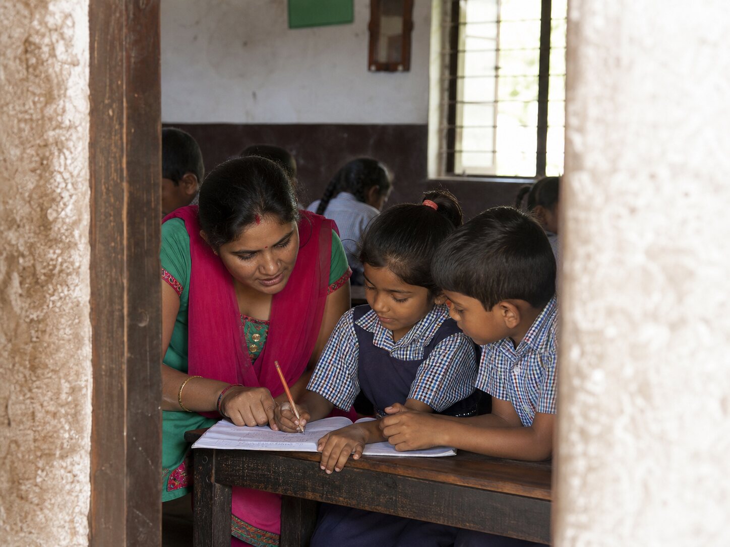 A teacher helping two children with their schoolwork